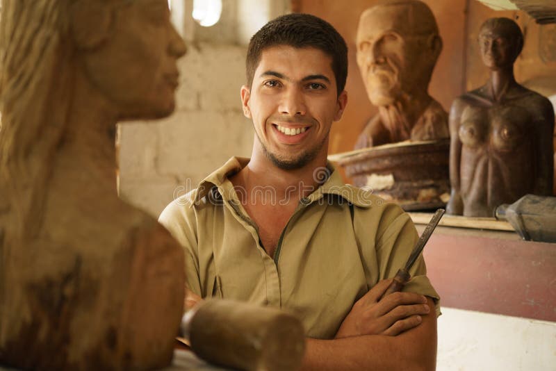 Portrait of man working, young student in art class, learning crafts profession, working with wooden statue and looking at camera. Portrait of man working, young student in art class, learning crafts profession, working with wooden statue and looking at camera