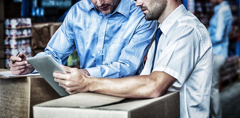 Portrait of managers are working with a tablet in the middle of cardboard boxes royalty free stock image Portrait of managers are working with a tablet in the middle of cardboard boxes royalty free stock image