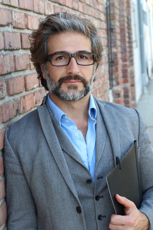 Portrait of mature business man with grey beard and hair alone outside modern creative office.