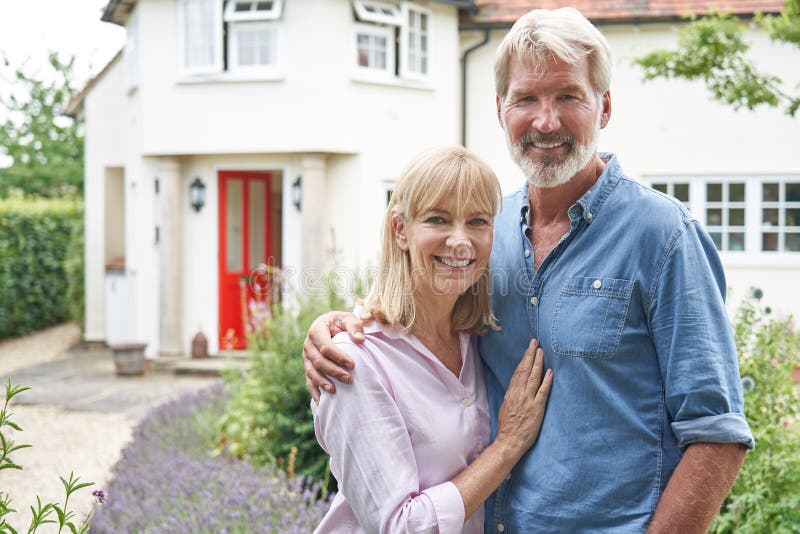 Portrait Of Mature Couple Standing In Garden In Front Of Dream Home In Countryside stock photography Portrait Of Mature Couple Standing In Garden In Front Of Dream Home In Countryside stock photography