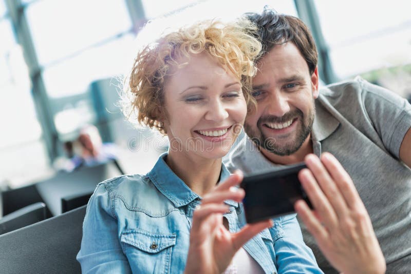 Portrait Of Mature Couple Taking And Looking At Their Selfie While Waiting For Boarding In 