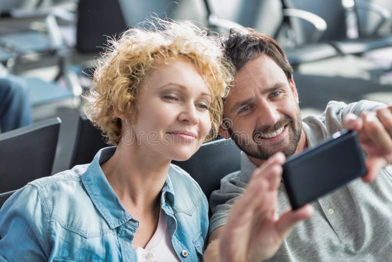 Portrait Of Mature Couple Taking Selfie While Waiting For Boarding In 