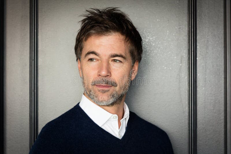 A portrait of a middle-aged bearded serious man looking away on a gray background