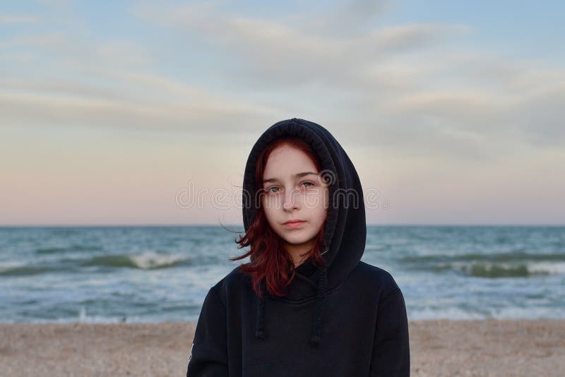 Portrait Of A Model In A Fashionable Jacket At Sunset By the sea. Teenager in a black hoodie and the sea. 9 years old