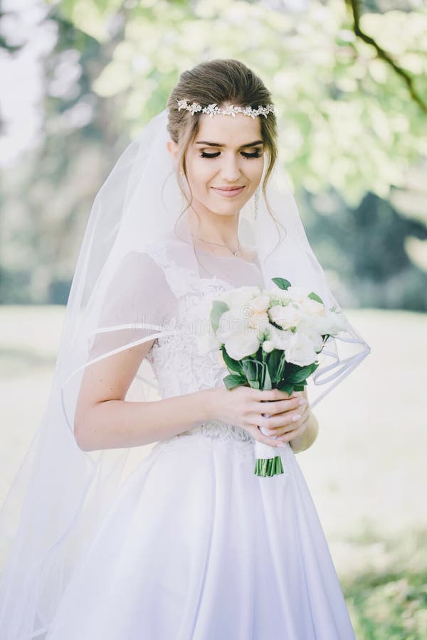 Portrait of modest bride in veil with a bouquet of flowers