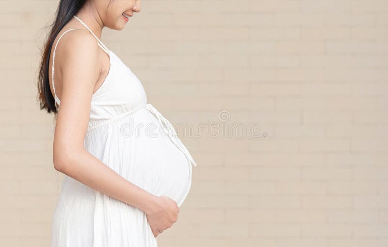 Portrait of 9 month pregnant young asian woman in white dress