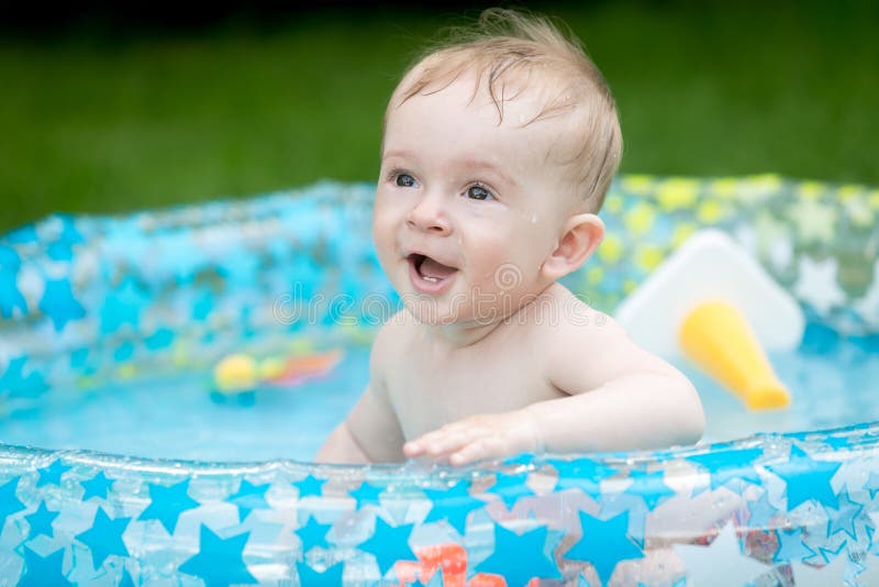 Portrait of 9 months old baby boy having fun in inflatable swimming pool