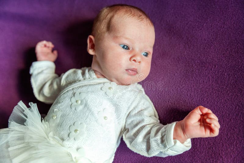 Portrait mou du bébé infantile nouveau-né doux paisible se trouvant sur le lit tout en dormant dans la couverture pourpre photographie stock Portrait mou du bébé infantile nouveau-né doux paisible se trouvant sur le lit tout en dormant dans la couverture pourpre photographie stock