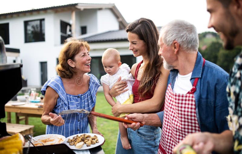 Portrait of multigeneration family outdoors on garden barbecue, grilling. Portrait of multigeneration family outdoors on garden barbecue, grilling and talking stock photography