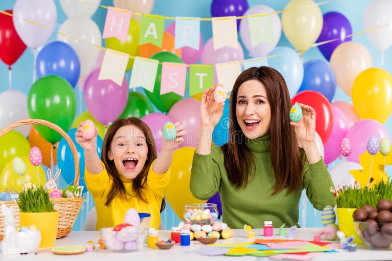 Portrait of nice attractive lovely creative glad cheerful cheery girls holding in hand colored eggs handicraft artwork stock images Portrait of nice attractive lovely creative glad cheerful cheery girls holding in hand colored eggs handicraft artwork stock images