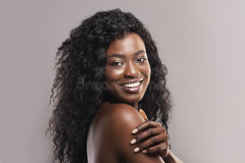 Portrait of nude beautiful afro woman smiling over grey background