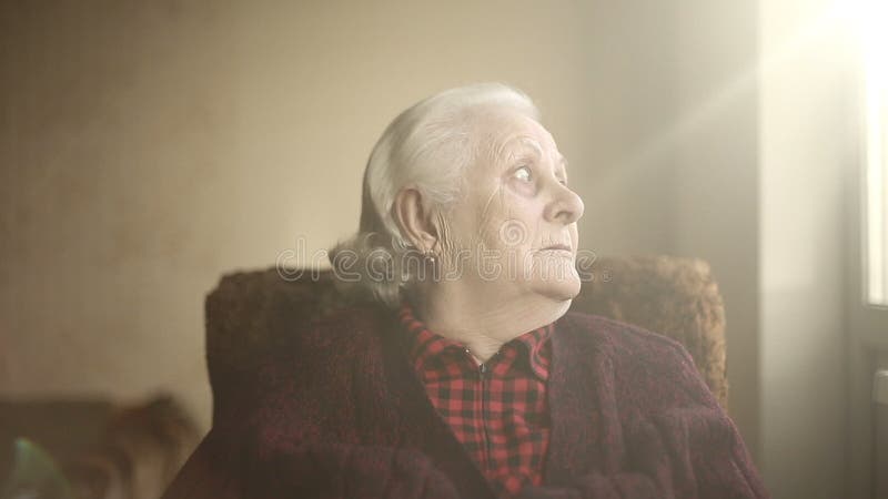 Portrait of an old lonely human who looks out the window