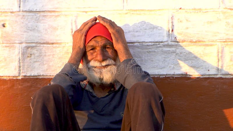 Portrait ou mi-photo d'un vieil homme assis sur le sol au coucher du soleil tenant son visage avec ses mains