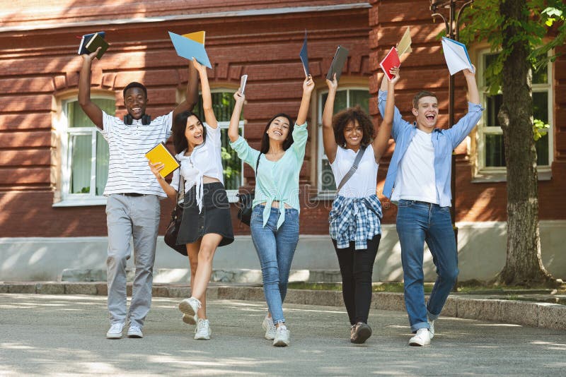 Portrait of overjoyed university students walking outdoors after successfully passing exam