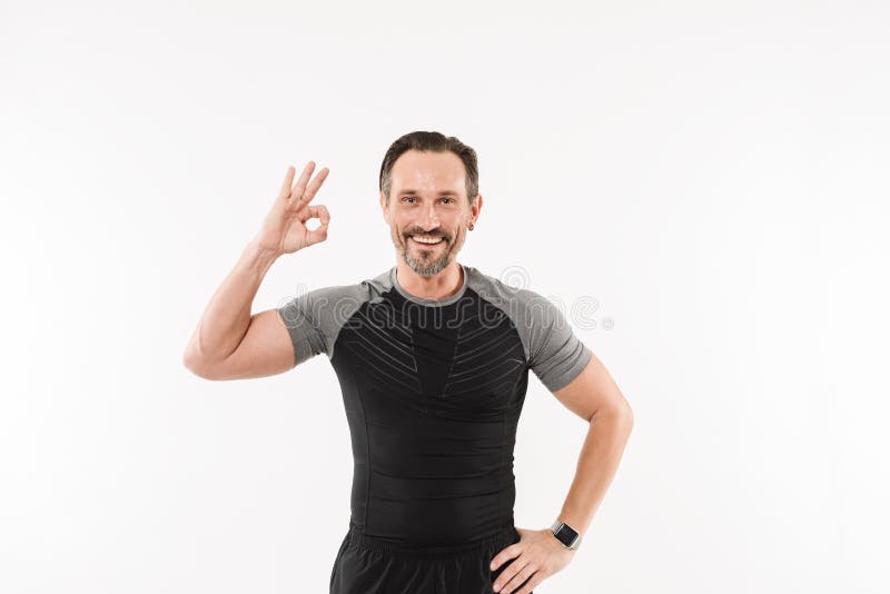 Portrait of pleased adult man fitness instructor smiling and gesturing ok sign after practising, isolated over white background stock photography Portrait of pleased adult man fitness instructor smiling and gesturing ok sign after practising, isolated over white background stock photography
