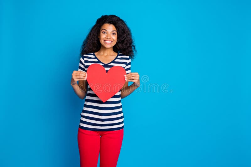 Portrait of positive cheerful afro american girl hold paper card big red heart present from romantic boyfriend on 14