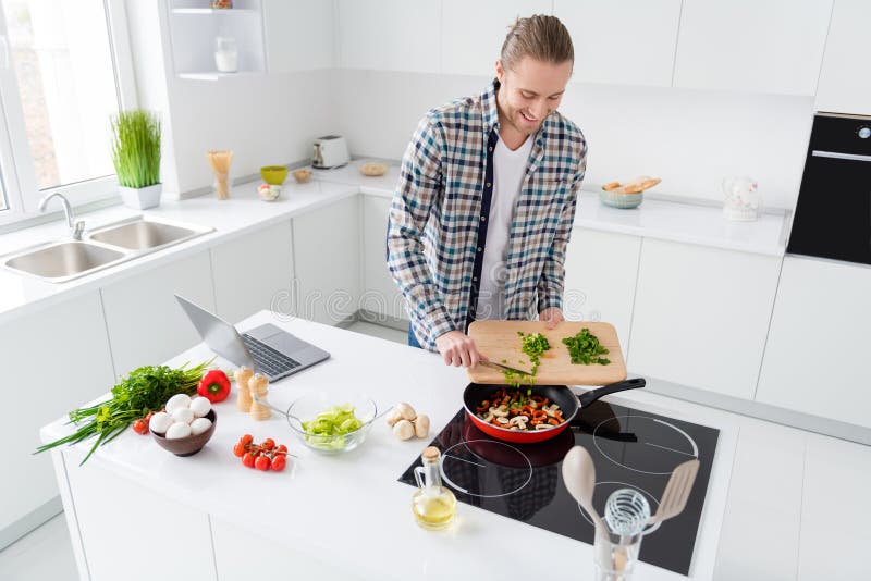 Portrait of positive guy chef have cooking hobby prepare dinner supper add fresh herbs to frying pan champignon pepper