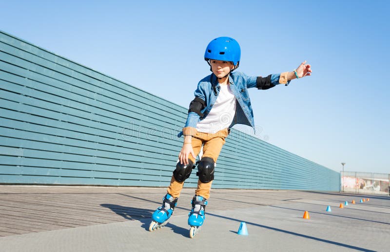 Boy learning to roller skate on road with cones