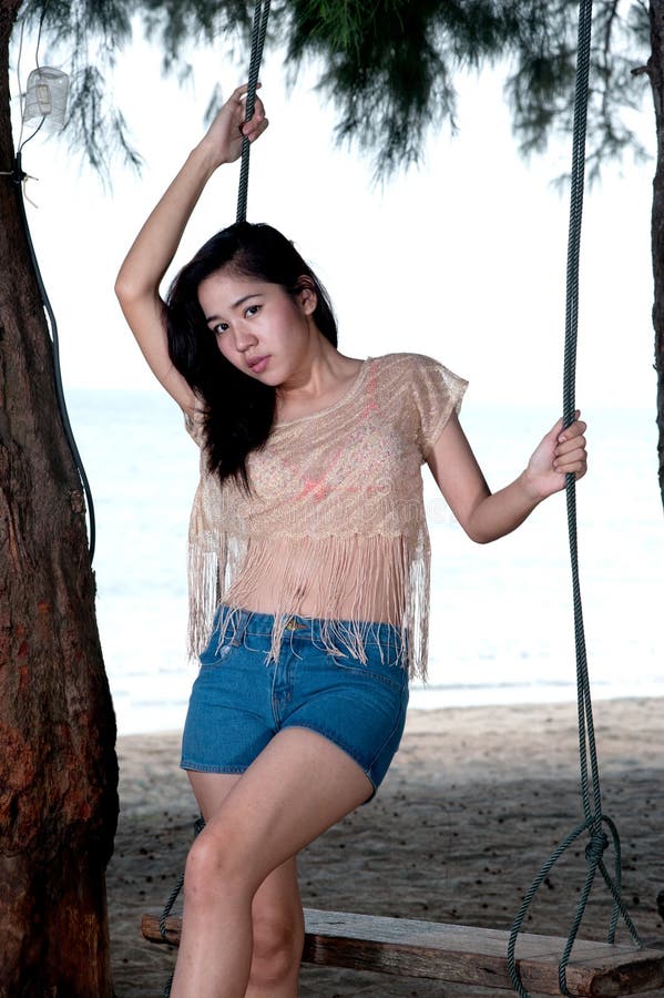 Portrait of pretty Asian woman standing on a swing .