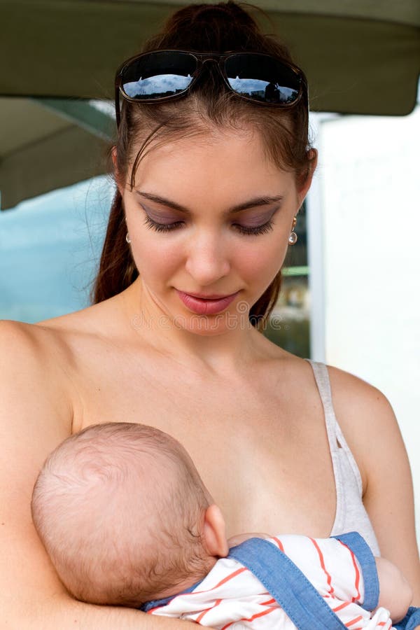 Portrait of pretty nursing mom holding her baby outside, cheerful loving young mother breastfeeding in public royalty free stock photography Portrait of pretty nursing mom holding her baby outside, cheerful loving young mother breastfeeding in public royalty free stock photography