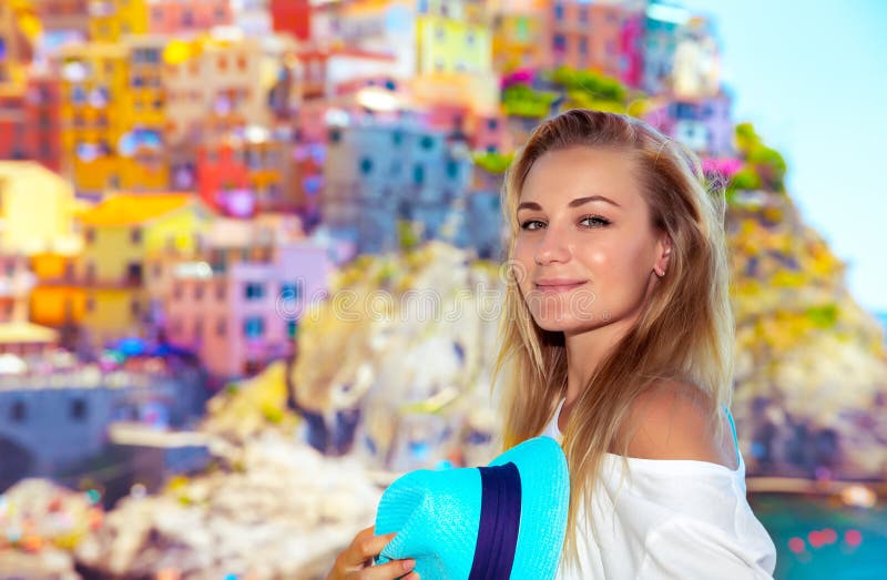 Portrait of a pretty traveler girl enjoying amazing view on a many colorful houses, active summer vacation, enjoying trip to Cinque Terre, Italy, Europe