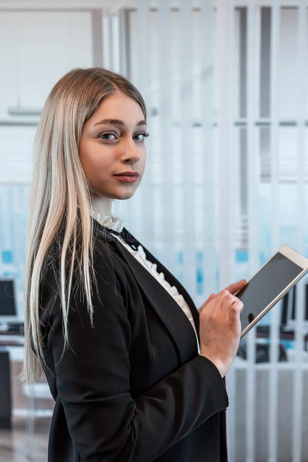 Portrait of pretty young caucasian holding modern computer tablet at office job stock photo