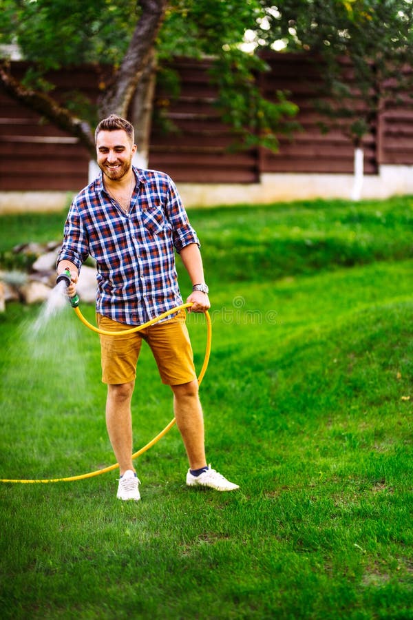 Portrait of Professional Gardener Watering Lawn Using Hose Stock Photo