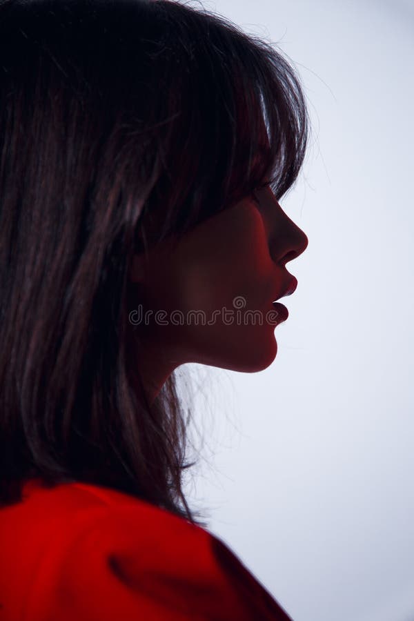 Portrait in profile a sexy brunette model, with big lips in red suit, elegant hairstyle, isolated on a white background. royalty free stock photo Portrait in profile a sexy brunette model, with big lips in red suit, elegant hairstyle, isolated on a white background. royalty free stock photo