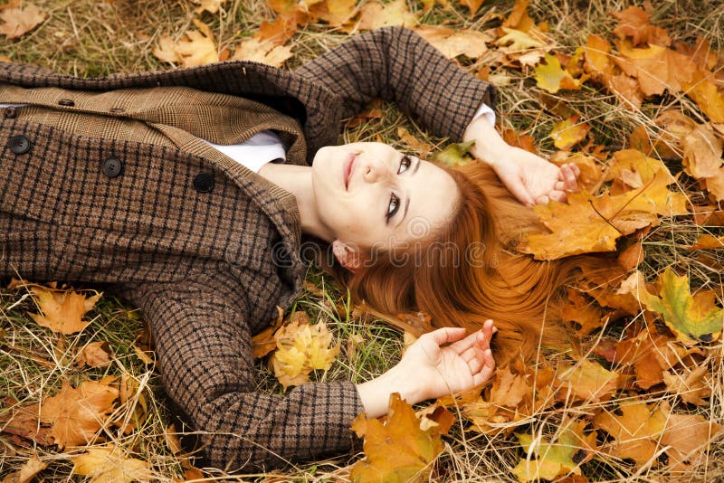 Portrait of red-haired girl in the autumn park.