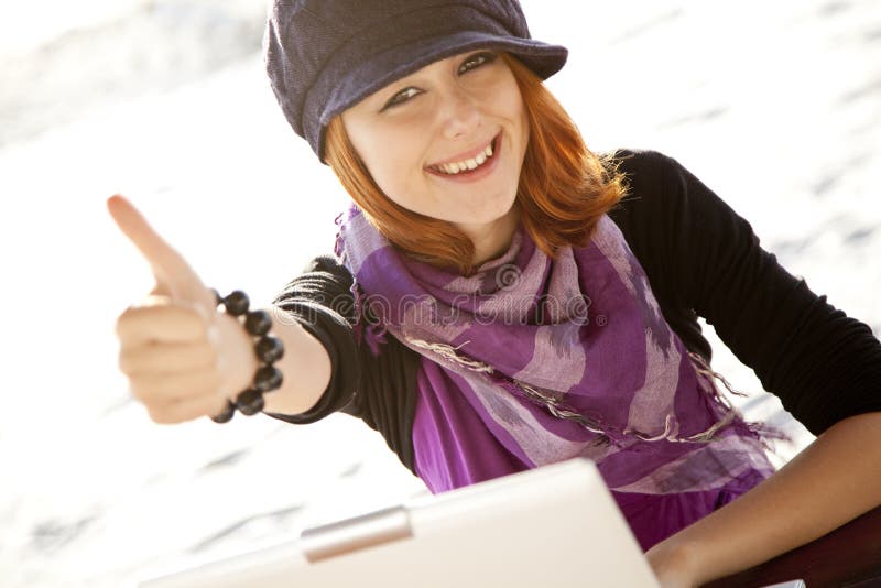 Portrait of red-haired girl with laptop at beach.