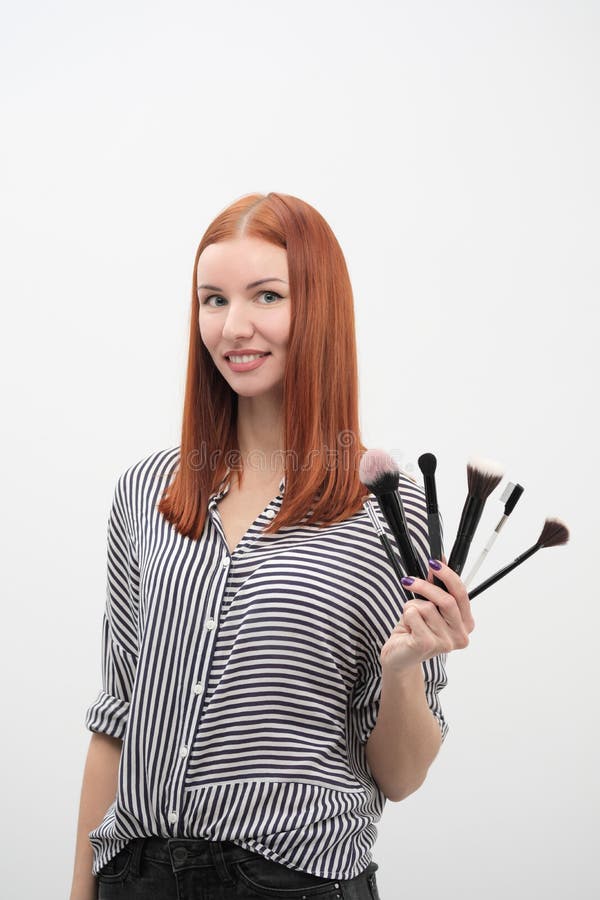Portrait of a red-haired girl, make-up of actor, professional on white background. Paint brushes and palette in hand. stock photography Portrait of a red-haired girl, make-up of actor, professional on white background. Paint brushes and palette in hand. stock photography