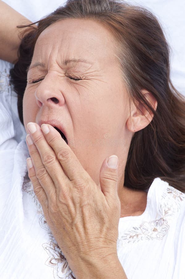 Tired mature woman yawning in bed royalty free stock photography Tired mature woman yawning in bed royalty free stock photography