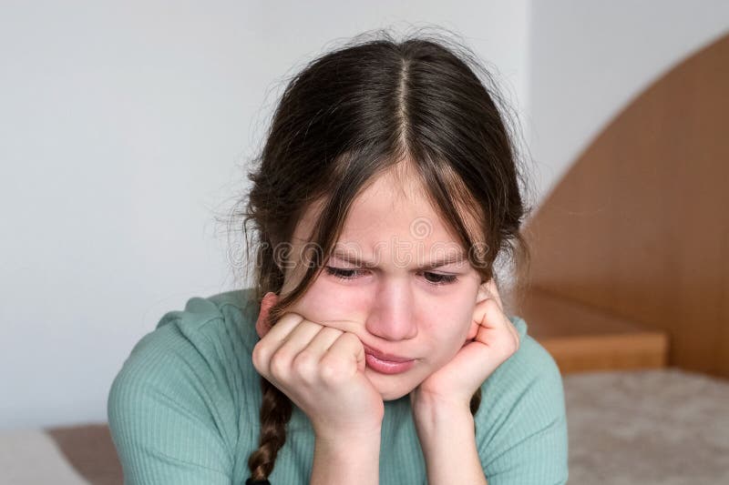 Portrait of sad little girl sitting on bed at home. Depressed kid with bad mood stock photos