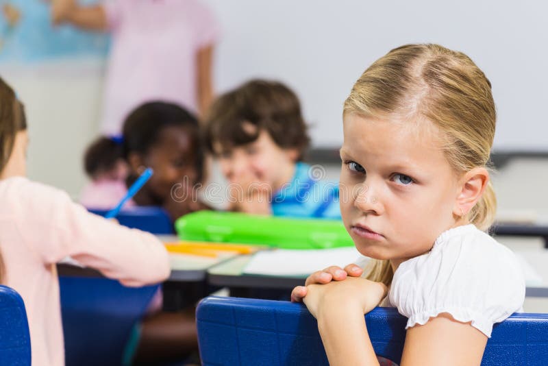 Portrait of sad schoolgirl sitting in the classroom at school