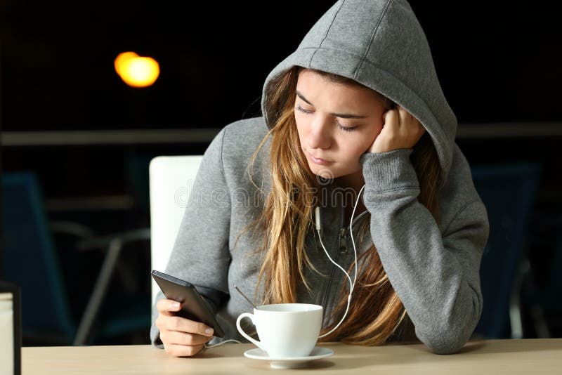 Sad teen listening to music with a smart phone and earphones