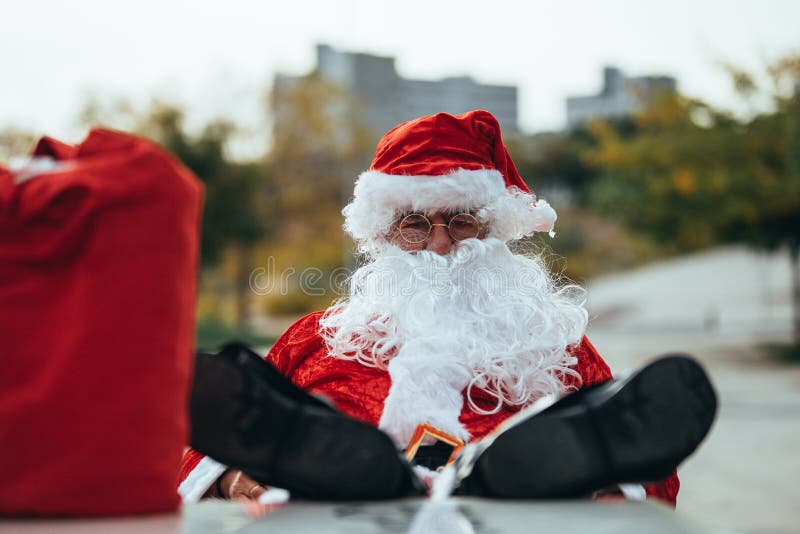 Portrait of Santa Claus sitting in a chair with his boots on the table with serious expression