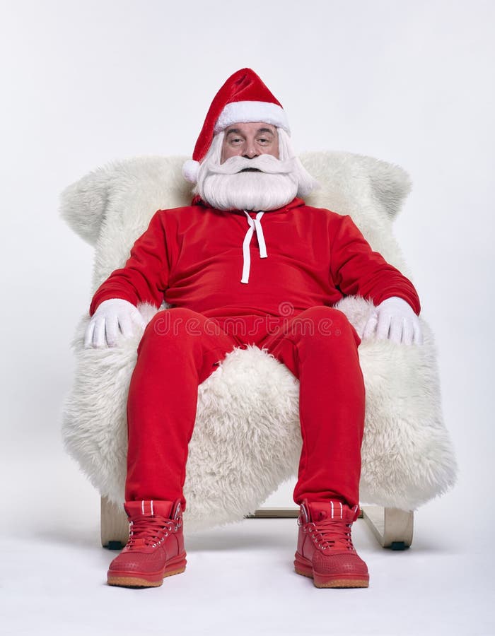 Portrait of a Santa Claus in sportsware sitting in a chair covered with sheepskin