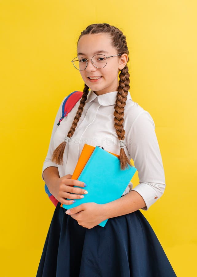 Portrait Of A Schoolgirl In Glasses With Books Textbooks On A Yellow 
