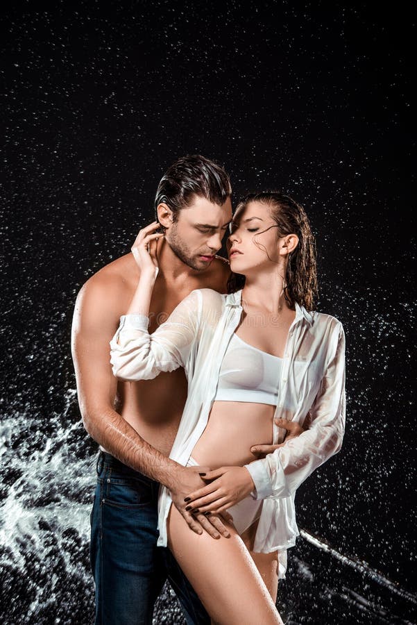 portrait of seductive couple swilled with water isolated on black