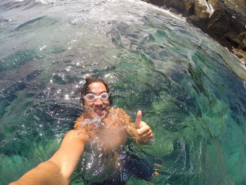 Portrait smiling boy selfie swimming in the sea with thumbs up. Portrait smiling boy selfie swimming in the sea with thumbs up