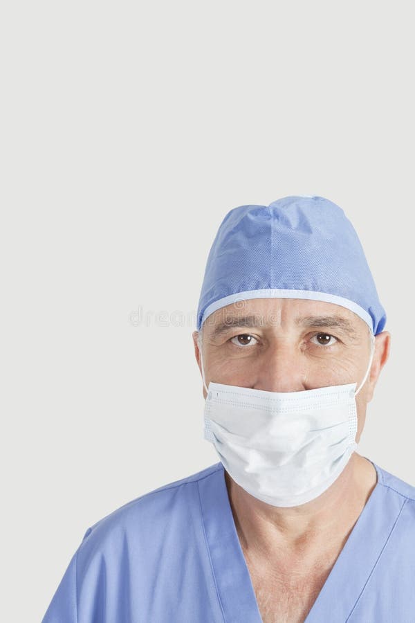 Portrait Of Senior Surgeon With Surgical Cap And Mask Over Gray