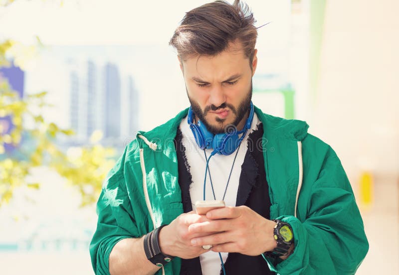 Confused man texting on mobile phone displeased with conversation walking on a street royalty free stock photo Confused man texting on mobile phone displeased with conversation walking on a street royalty free stock photo