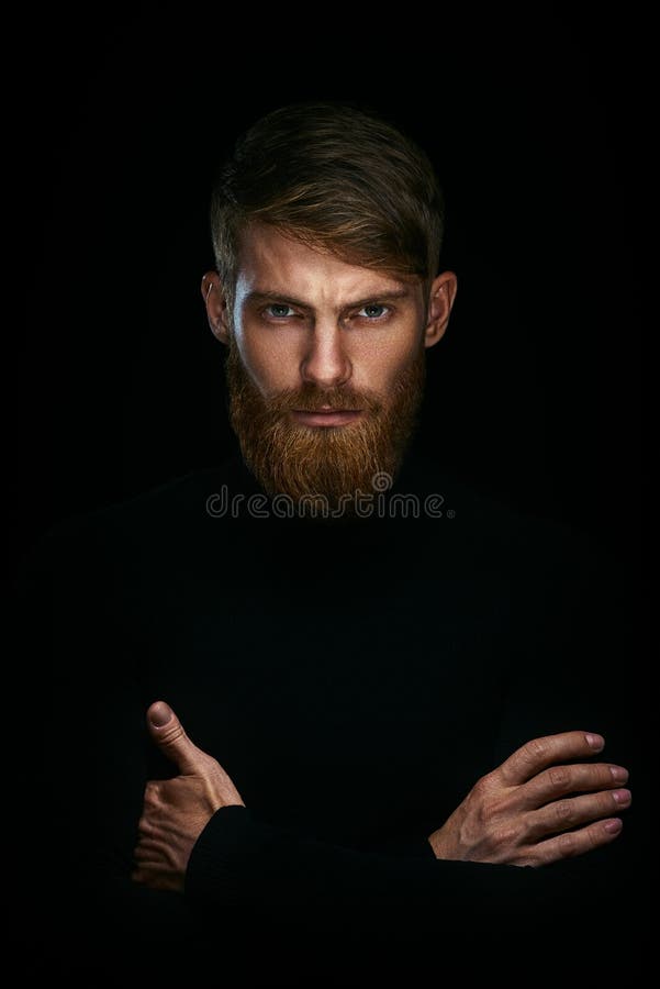 Portrait of serious young man with folded and crossing hands sta