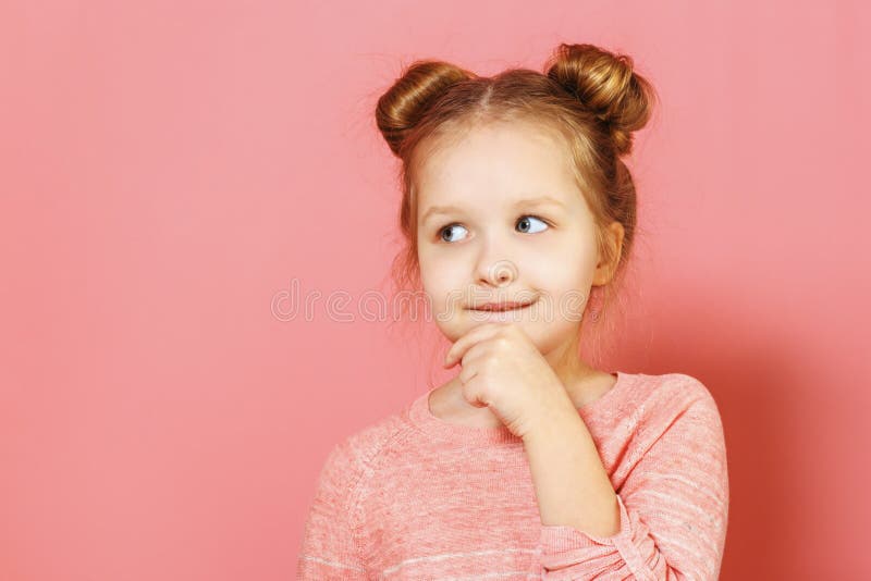 Portrait serré d'une jolie petite fille chatoyante et fascinante, avec des petits pains, à l'air réfléchi de côté photographie stock Portrait serré d'une jolie petite fille chatoyante et fascinante, avec des petits pains, à l'air réfléchi de côté photographie stock