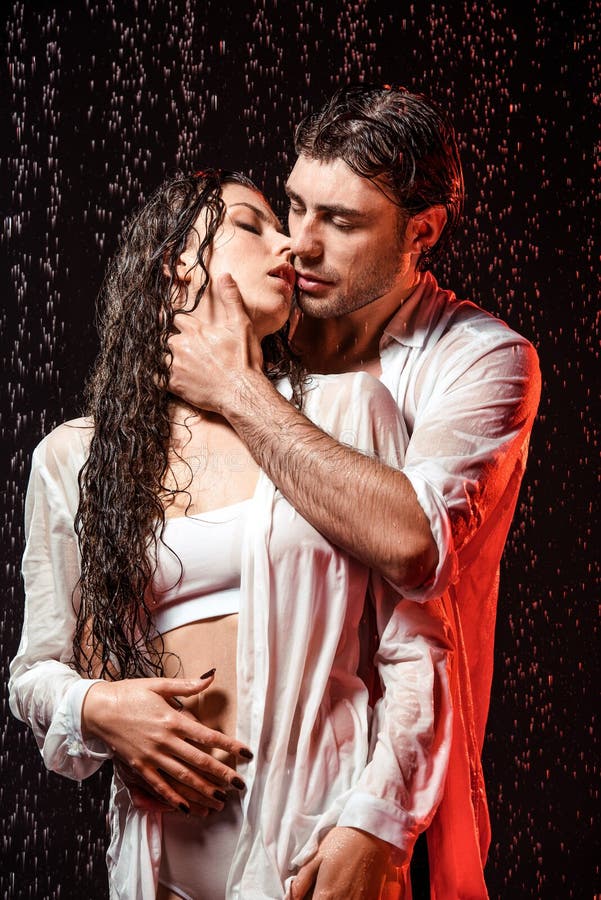 portrait of sexy couple in white shirts standing under rain