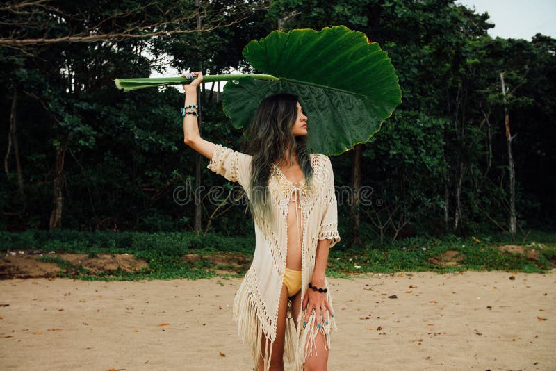 Portrait young woman in bikini and tunic with large leaf tropical tree
