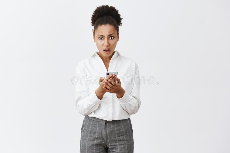 Portrait of shocked confused and displeased good-looking african-american woman in suit, holding smartphone and staring stock photo Portrait of shocked confused and displeased good-looking african-american woman in suit, holding smartphone and staring stock photo