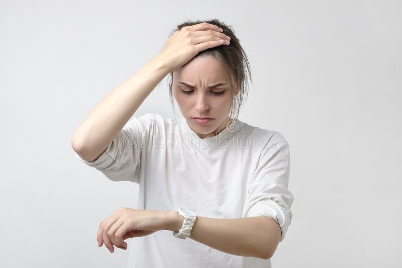 Portrait of shocked sad young woman holding hand with wrist watch. stock photo Portrait of shocked sad young woman holding hand with wrist watch. stock photo