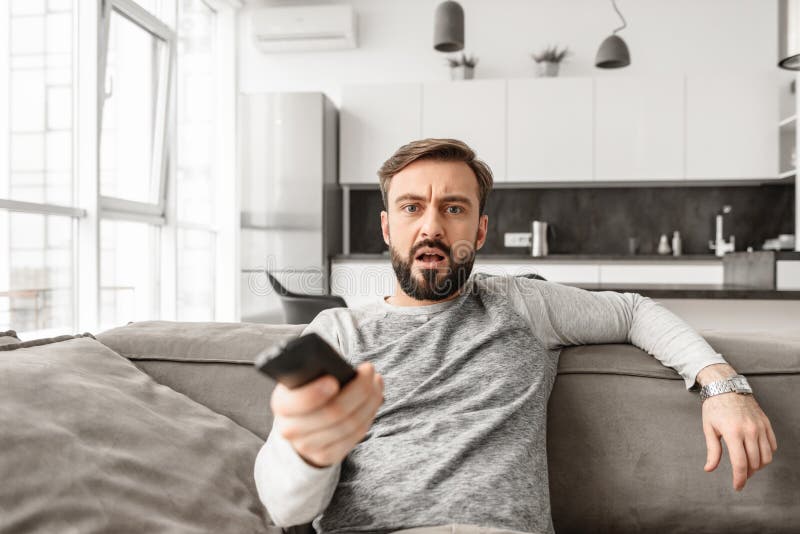 Portrait of a shocked young man holding TV remote control royalty free stock images Portrait of a shocked young man holding TV remote control royalty free stock images
