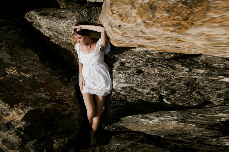 Portrait of slender young woman on stones near the sea royalty free stock photo Portrait of slender young woman on stones near the sea royalty free stock photo